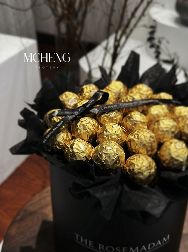 Chi Tiet Hop Hoa Socola Ferrero Mcheng Florist Cận cảnh những viên socola Ferrero Rocher vàng ánh kim nổi bật trên nền đen