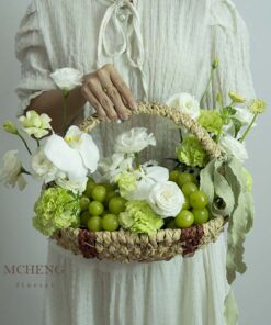 Góc nghiêng tôn lên chiếc giỏ cói mộc mạc và nơ lụa xanh rêu của lẵng trái cây