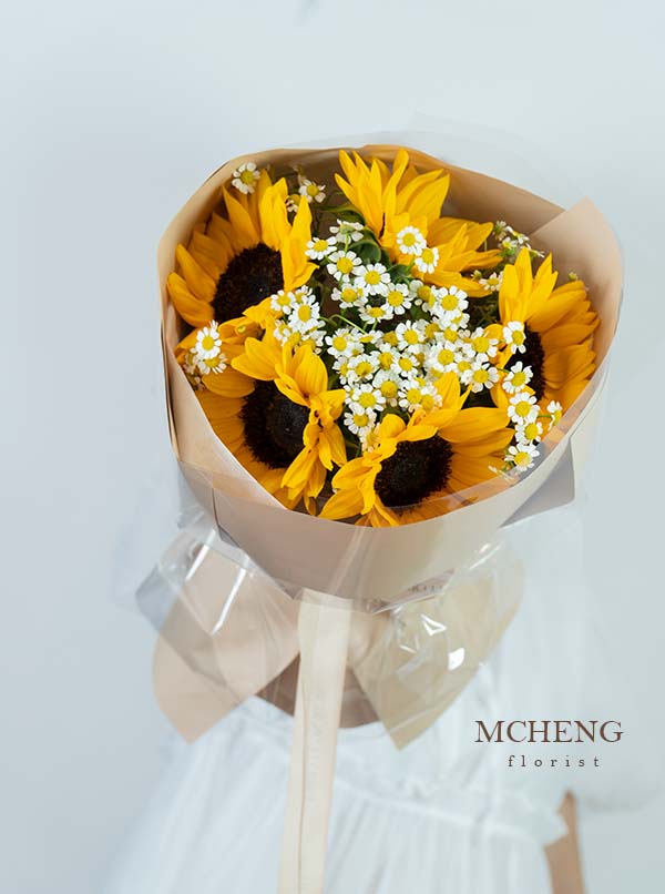 Hoa Bó Tốt Nghiệp Hướng Dương Mix Cúc Tana Khởi Đầu - Mcheng Florist Mẫu hoa bó tốt nghiệp hướng dương mix cúc tana bọc kính trong suốt tại Mcheng Florist