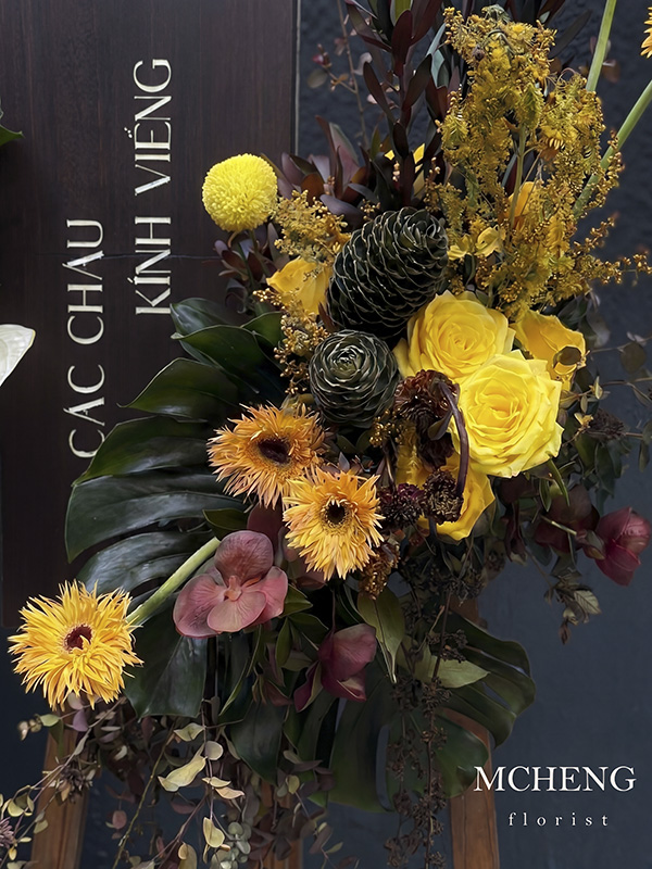 Chi Tiet Ke Hoa Chuc Mung Tone Vang Den Mcheng Florist Cận cảnh sự tương phản giữa hoa hồng vàng và lá đen trên kệ hoa chúc mừng nghệ thuật