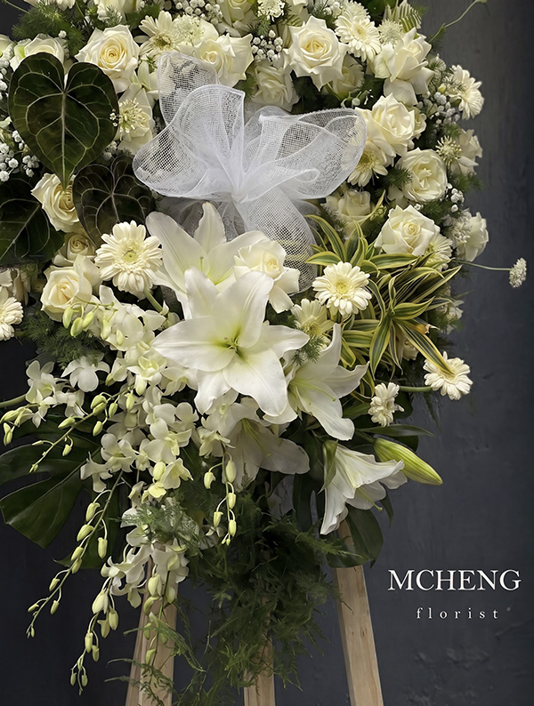 Chi Tiet Ke Hoa Chia Buon Tone Trang Xanh Mcheng Florist Cận cảnh vẻ đẹp thanh tịnh của hoa Ly trắng và lá Hồng Môn xanh trên kệ hoa chia buồn
