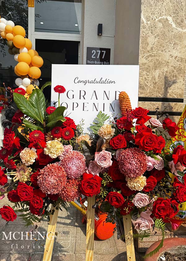 Kệ Hoa Khai Trương Chân Gỗ Đỏ Bừng Sáng - Mcheng Florist Hình ảnh thực tế Kệ Hoa Khai Trương Chân Gỗ Tone Đỏ đặt tại sảnh sự kiện chúc mừng khai trương